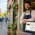 Mala preduzetnica ispred lokala koristi laptop i telefon za sređivanje Google profila, mape i osnovnih podataka lokalnog biznisa